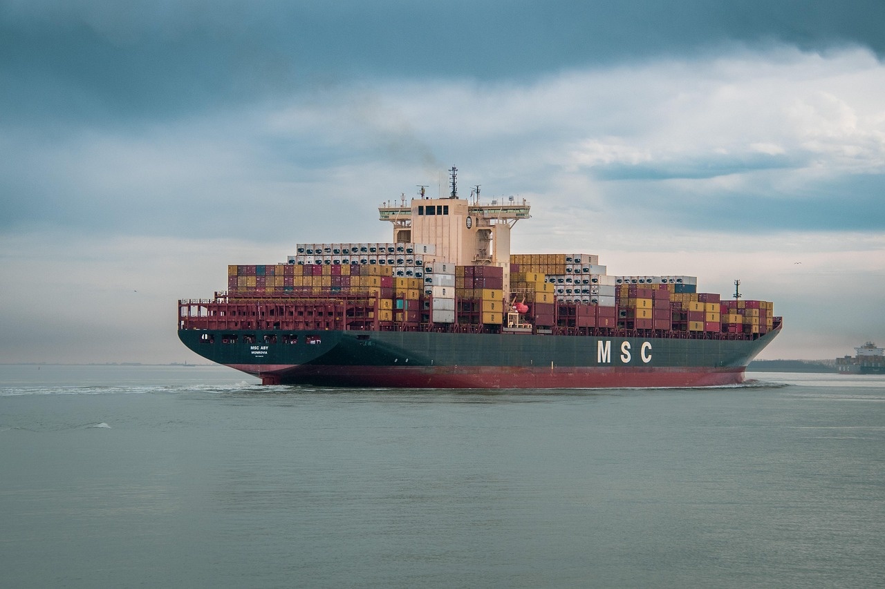 Containerschiff mit gestapelter Ladung auf ruhigem Wasser unter bewölktem Himmel