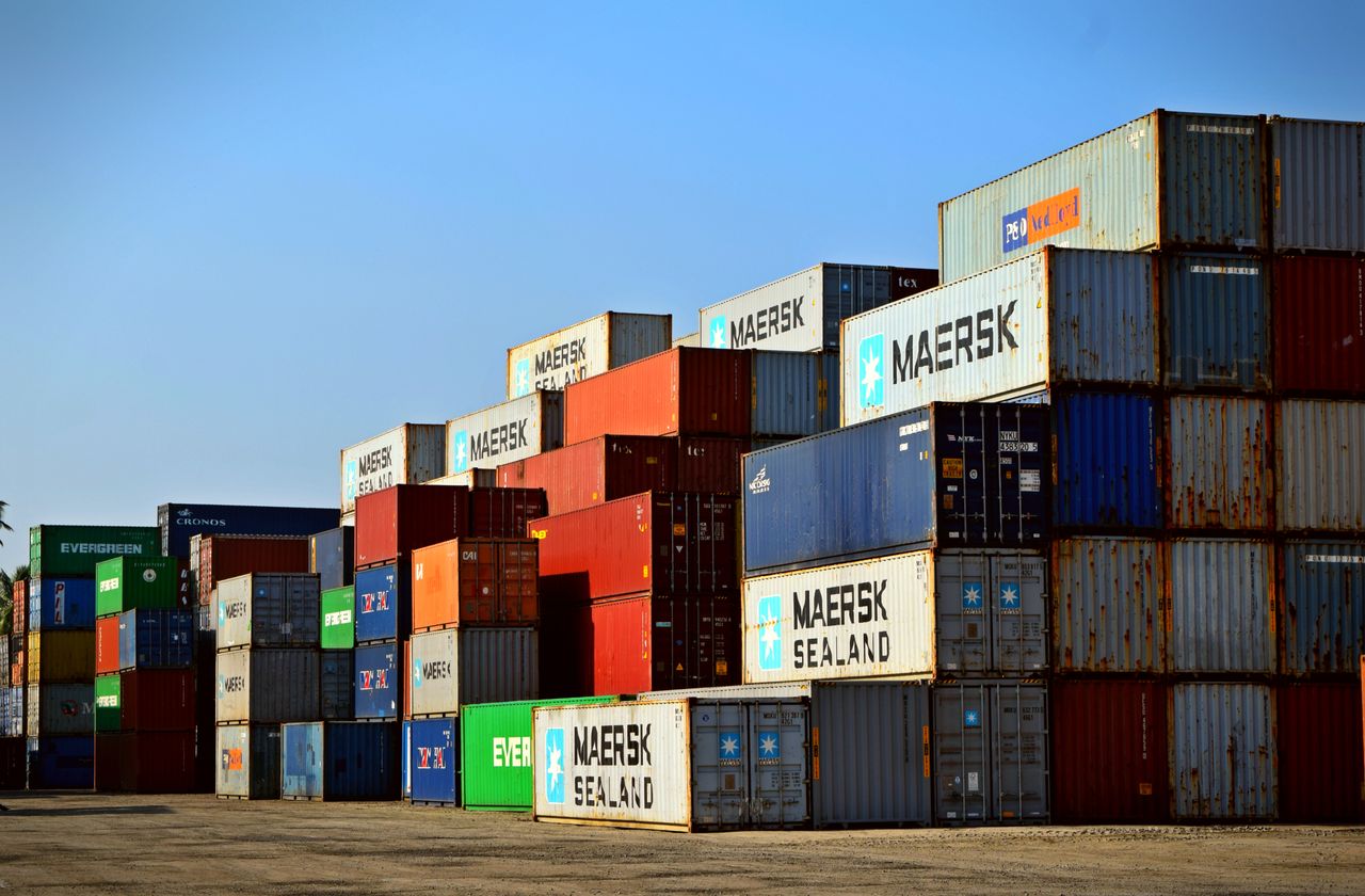 Gestapelte Seecontainer in einem Terminalgelände vor klarem Himmel