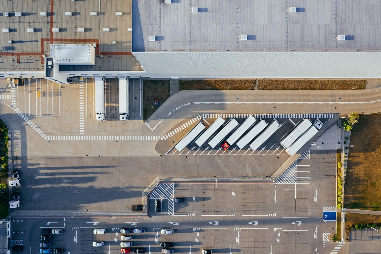 Luftaufnahme eines Distributionszentrums mit Laderampen, Trailern und markierten Fahrwegen